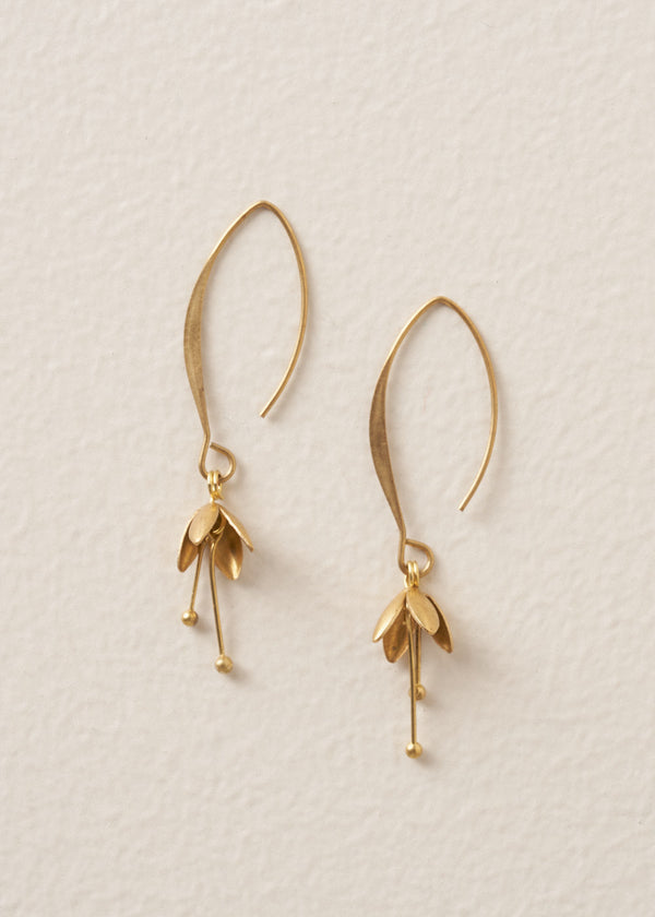 Gold blossom drop earrings on a beige background