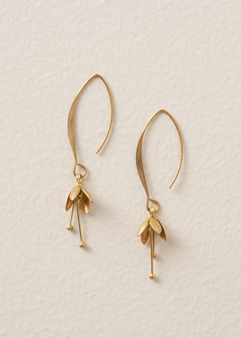 Gold blossom drop earrings on a beige background