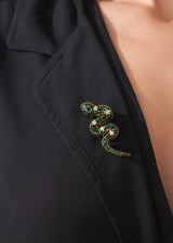 Sparkling snake brooch with twinkling green crystals on a classic pin fastening, photographed on a black blazer