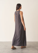 Woman wearing a long, dark gray dress with textured stripes against a plain background