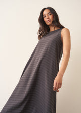 Woman wearing a long, dark gray dress with textured stripes against a plain background