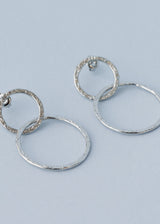 Hammered silver interlocking hoop earrings on blue background