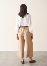 Woman wearing light beige cropped wide leg trousers, matching beige jacket and a white top.