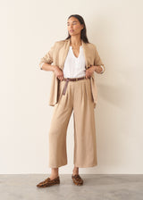 Woman wearing light beige cropped wide leg trousers, matching beige jacket and a white top.