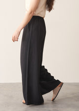 Woman wearing black wide leg trousers with nude camisole and light cardigan