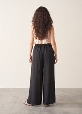 Woman wearing black wide leg trousers with nude camisole and light cardigan