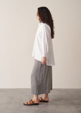 Woman wearing an oversized white shirt and grey stripe trousers