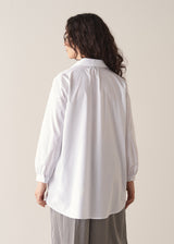 Woman wearing an oversized white shirt and grey stripe trousers