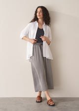 Woman wearing an oversized white shirt and grey stripe trousers