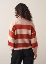 Woman wearing a red and blush pink striped cardigan with black trousers