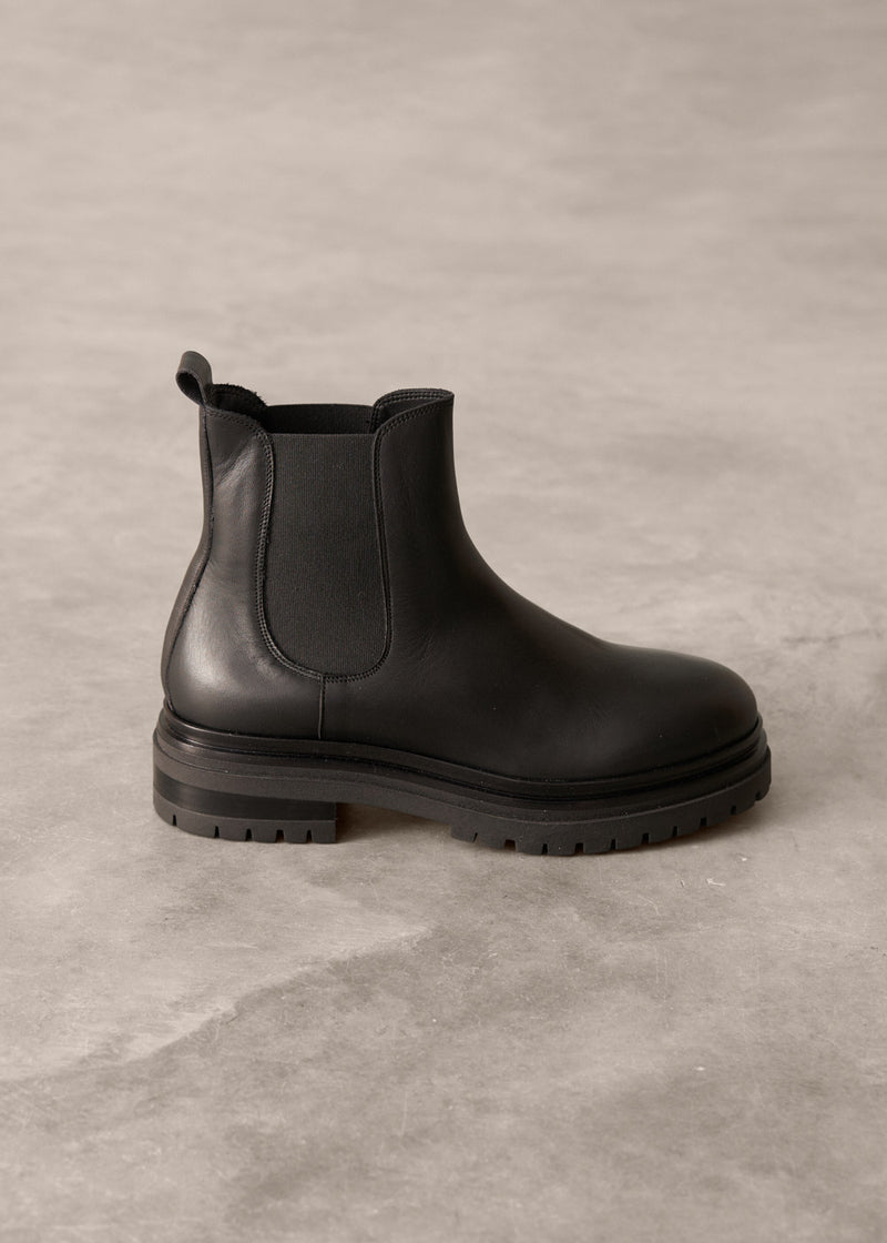 Short black leather Chelsea boot on a gray concrete surface