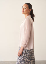 Woman wearing oyster pink satin blouse with leopard print trousers