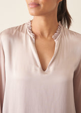 Woman wearing oyster pink satin blouse with leopard print trousers