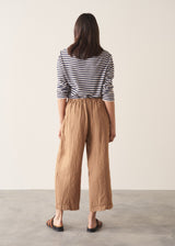 Woman wearing brown straight-leg ankle length linen trousers with a stripe breton top