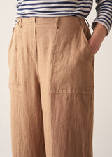 Woman wearing brown straight-leg ankle length linen trousers with a stripe breton top