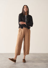 Woman wearing brown straight-leg ankle length linen trousers with a stripe breton top