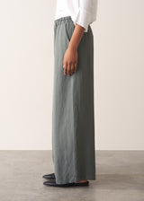 Woman wearing a white shirt with grey wide leg, full length linen blend trousers and kitten heels