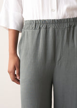 Woman wearing a white shirt with grey wide leg, full length linen blend trousers and kitten heels