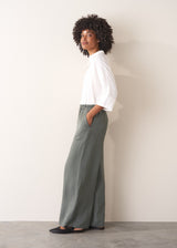 Woman wearing a white shirt with grey wide leg, full length linen blend trousers and kitten heels