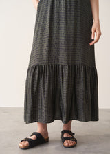 Person wearing a black patterned dress on a plain background
