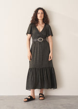 Woman wearing a green and black patterned dress against a white wall