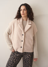 Woman wearing a beige boucle gilet over oatmeal sweater with leopard print trousers 