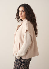 Woman wearing a beige boucle gilet over oatmeal sweater with leopard print trousers 