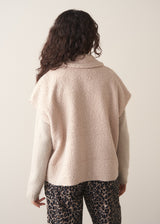 Woman wearing a beige boucle gilet over oatmeal jumper with leopard print trousers 