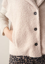 Close up of woman wearing a beige boucle gilet over with leopard print trousers 