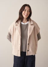 Woman wearing an oatmeal boucle gilet with a grey sweater and blue jeans