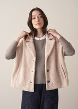 Woman wearing an oatmeal boucle gilet with a grey sweater and blue jeans