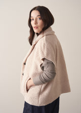 Woman wearing an oatmeal boucle gilet with a grey sweater and blue jeans