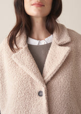 Woman wearing an oatmeal boucle gilet with a grey sweater and blue jeans