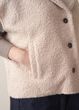 Woman wearing an oatmeal boucle gilet with a grey sweater and blue jeans