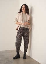 Woman wearing a beige boucle gilet over oatmeal jumper with leopard print trousers and chunky boots