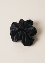 Black velvet hair scrunchie on a beige background