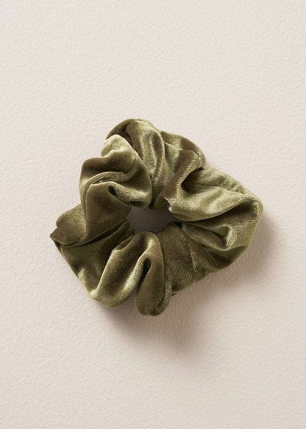 Green velvet hair scrunchie on a beige background
