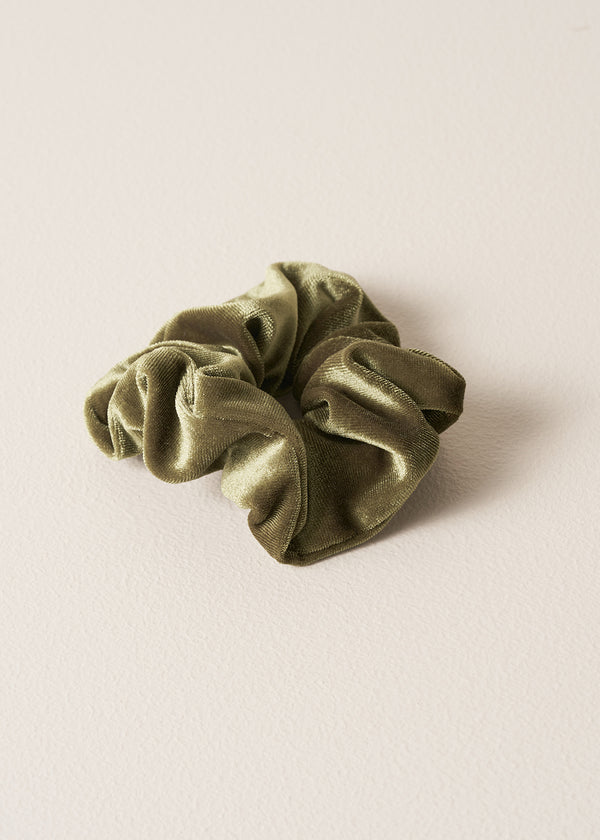 Green velvet hair scrunchie on a beige background