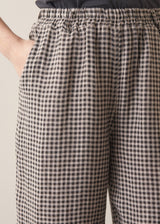 Close up of woman wearing grey checked cropped linen barrel leg trousers with grey vest top