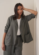 Woman wearing a khaki linen blazer and barrel leg linen trousers