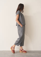 Woman wearing blue and green checked linen barrel leg trousers and a white top.