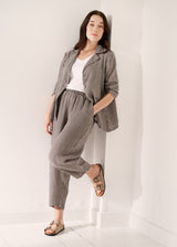 Woman wearing grey checked cropped linen barrel leg trousers and matching grey checked linen jacket with a white vest top
