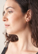 Gold hoop earrings with red crystal detail