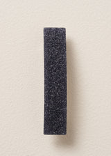 Black glitter hair clip on beige background