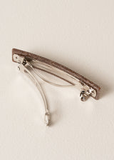 Side view of brown glittery hair clip on beige background