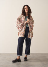 Woman wearing a space dye patterned oversized cardigan and blue jeans against a plain background