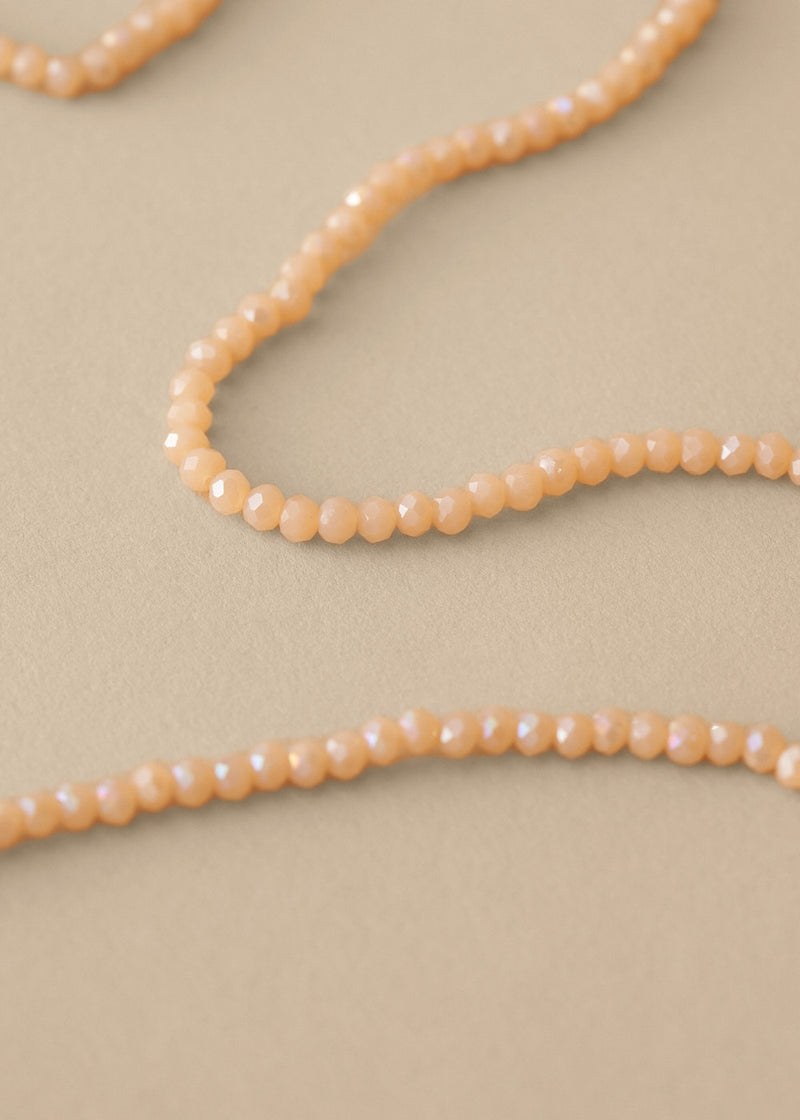 Close up of long nude beaded necklace on beige background