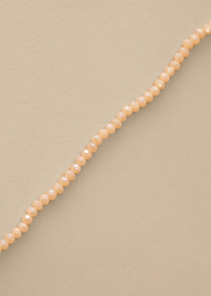 Close up of long nude beaded necklace on beige background