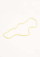 A long yellow crystal necklace on a beige background