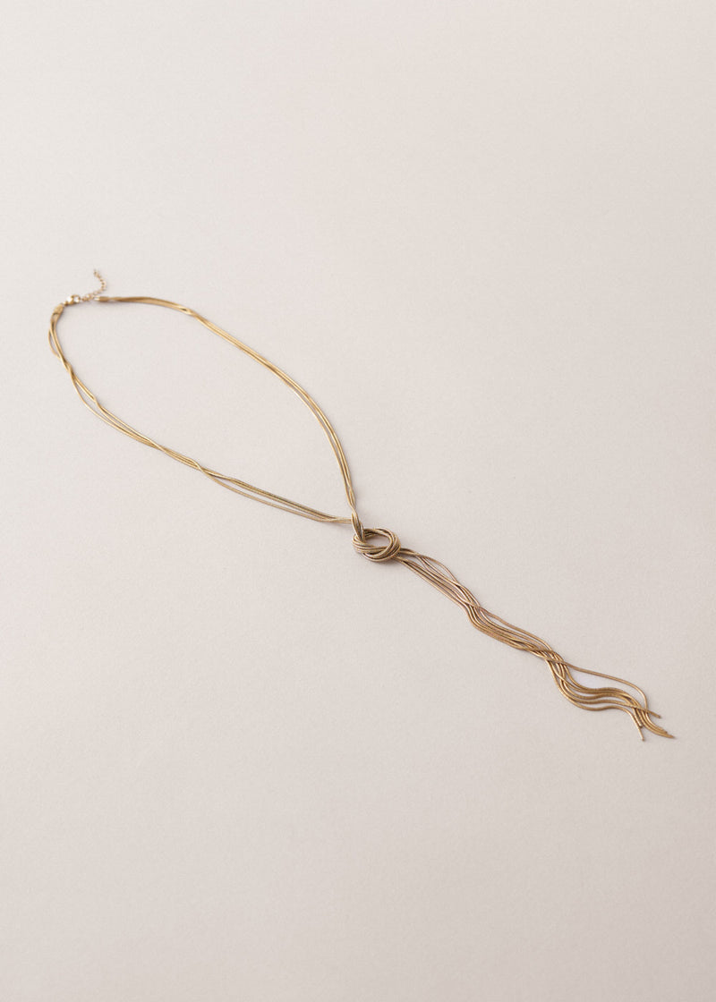 Gold chain knot necklace on a beige background